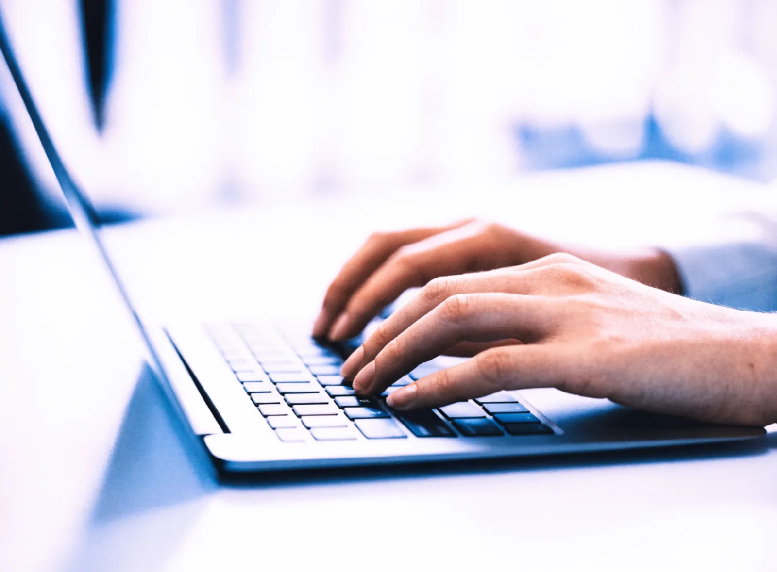 Hände tippen auf einer Laptop-Tastatur