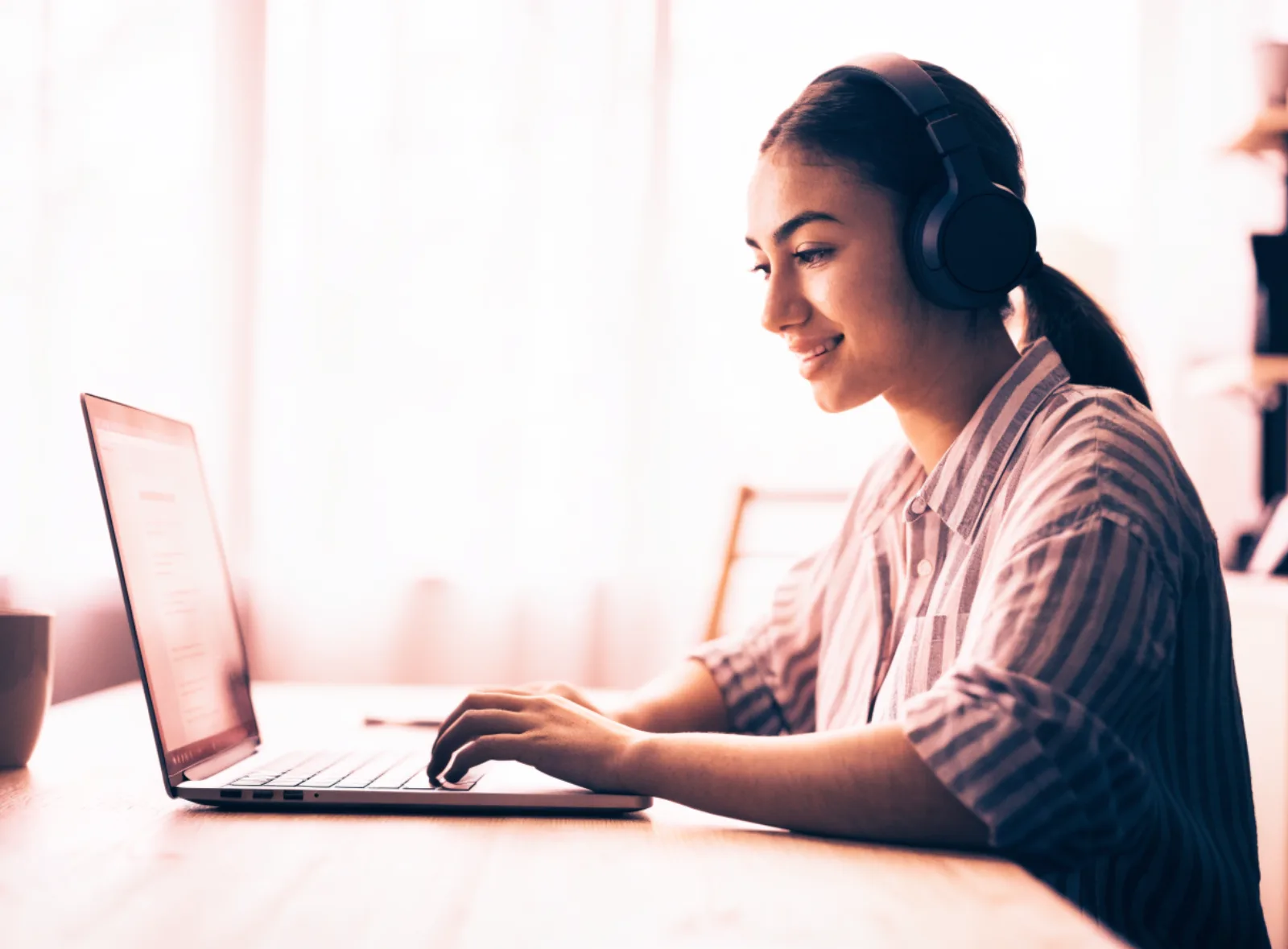 Teilnehmerin mit Kopfhörern folgt einem Online-Kurs am Laptop